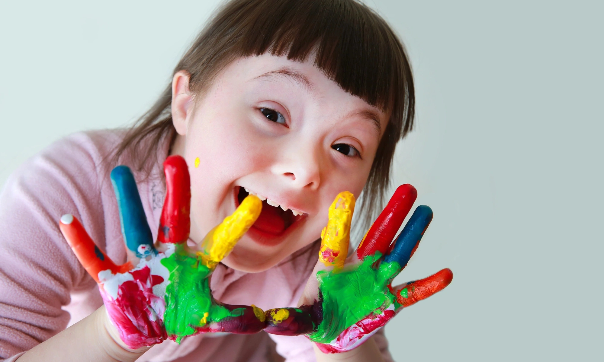 A beautiful child with down syndrome, showing her painted hands